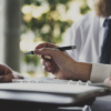 Zwei Personen in Businesskleidung arbeiten an einem Laptop und überprüfen Unterlagen, symbolisierend die Planung und Eigenständigkeit beim provisionsfreien Immobilienverkauf.